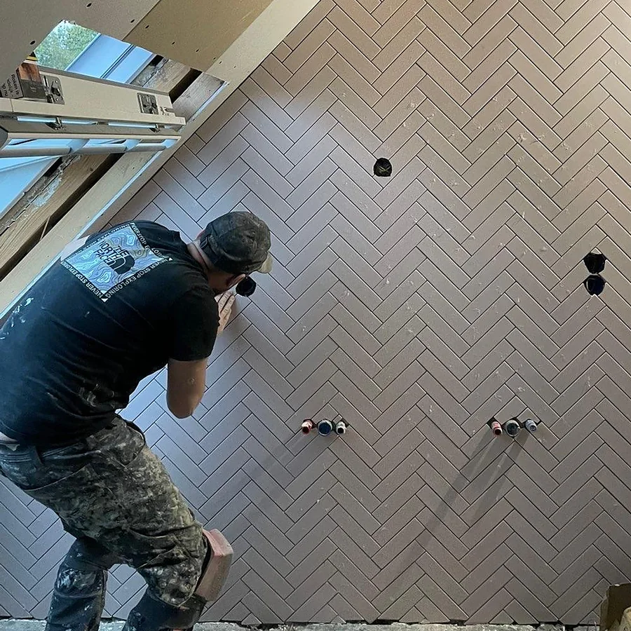 Tegelzetter werkt een visgraatwand af in een zolderbadkamer